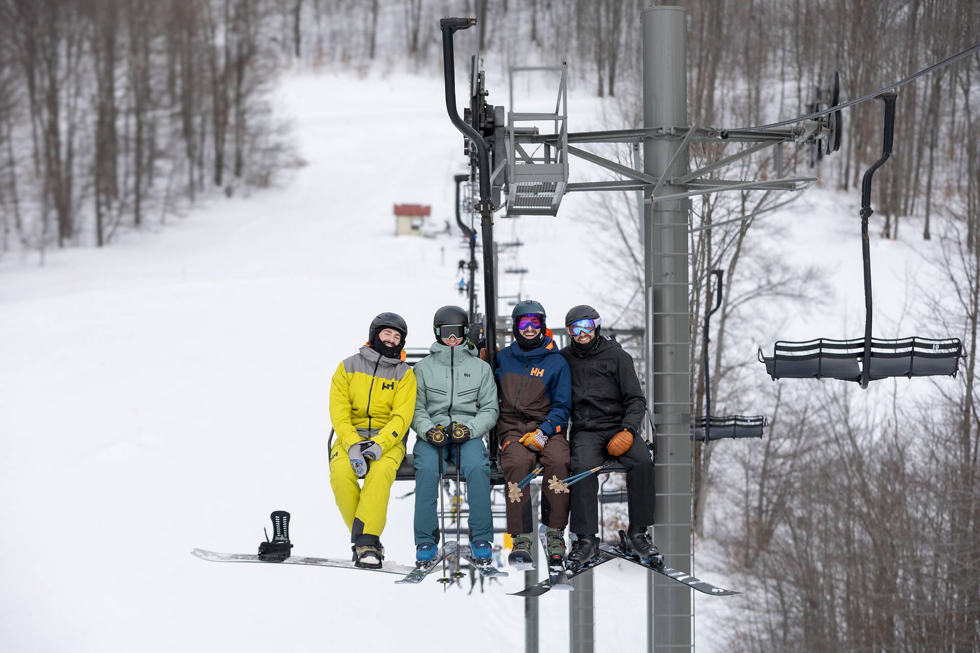 A group of skiers and snowboarders posing on the chairlift
