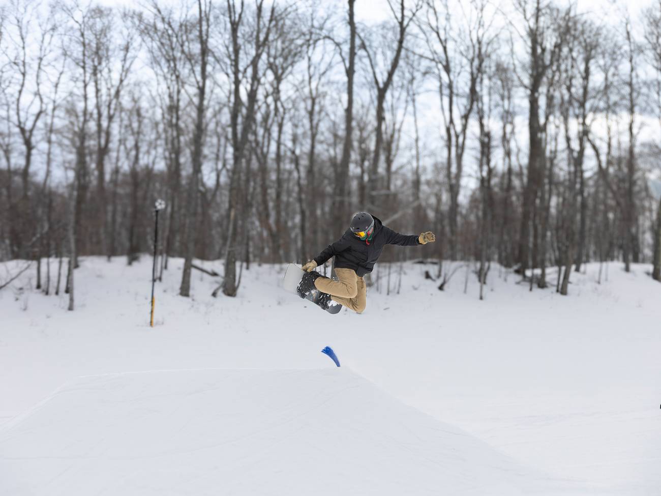 A snowboarder jumping on a snow feature