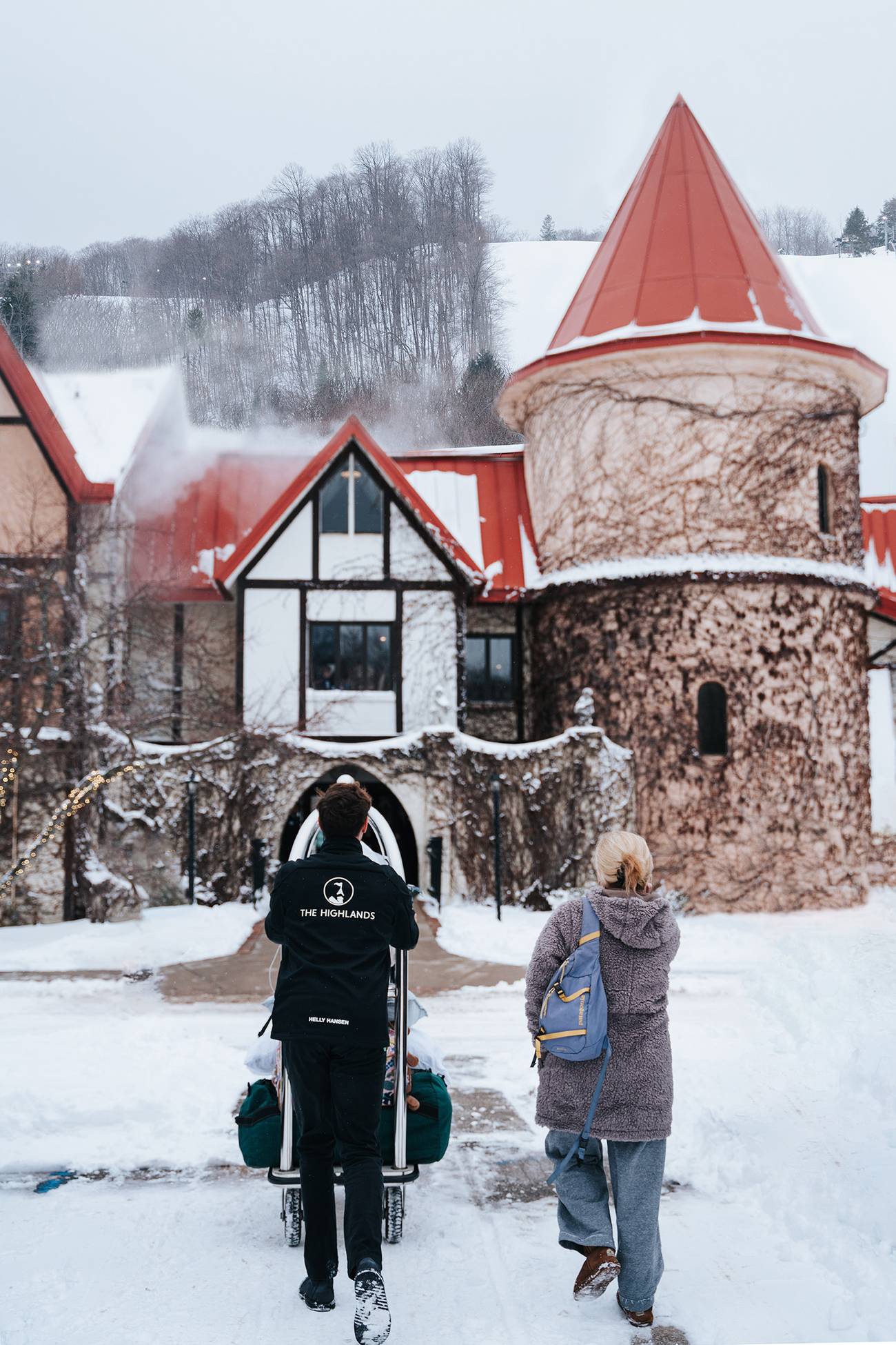 A bellhop taking bags inside during winter