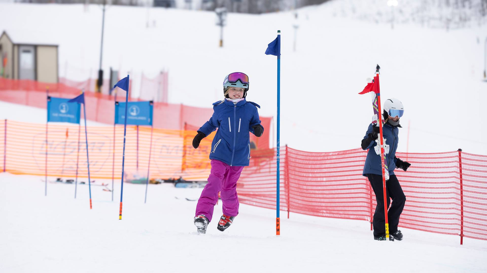 A kid in ski boats and winter gear racing around poles