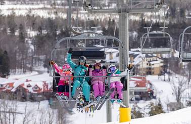 A family posing on a chairlift in ski gear at The Highlands