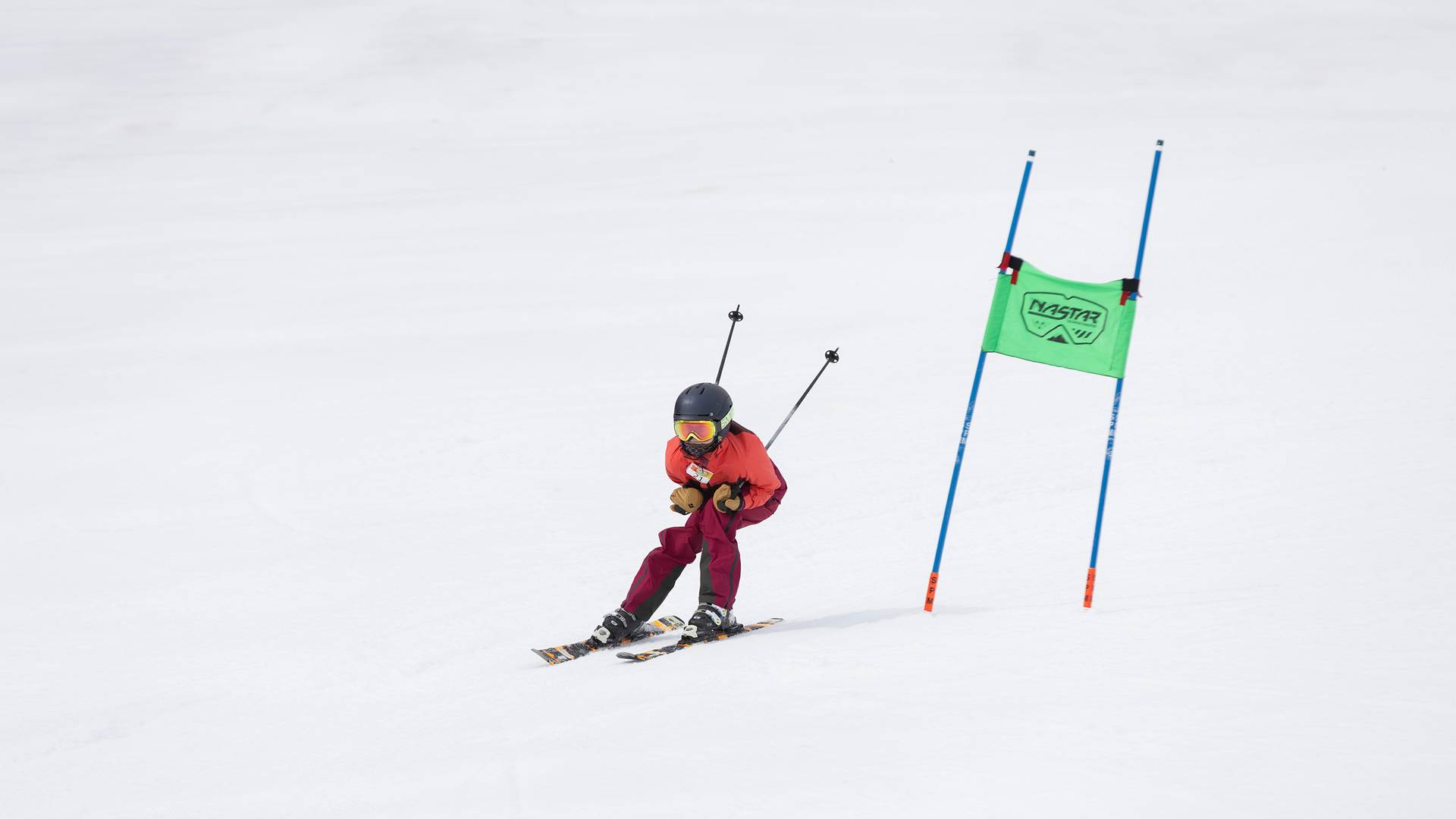 A girl in ski race gear racing at The Highlands on the NASTAR course.
