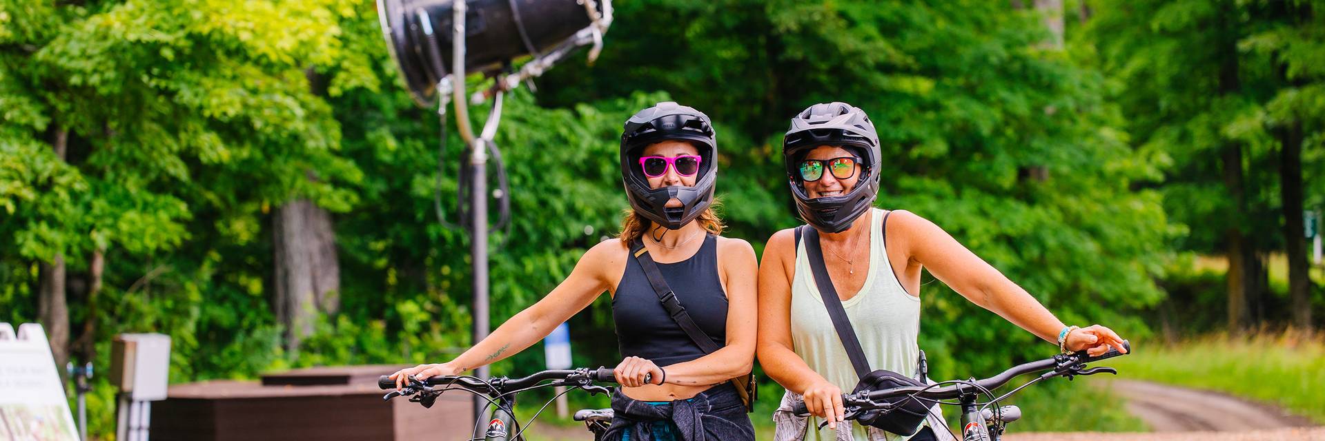 Two women posing in mountain bike gear with their bikes
