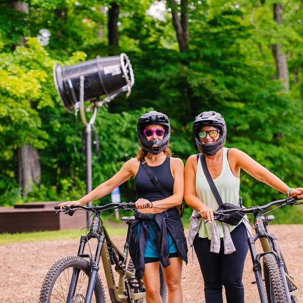 Two women posing in mountain bike gear with their bikes