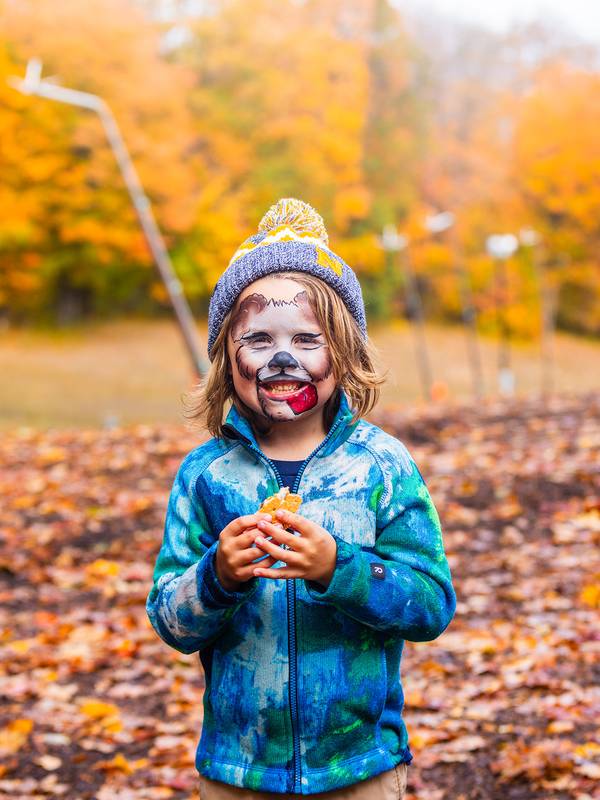A boy smiling with his face painted during the Harvest Fest at The Highlands