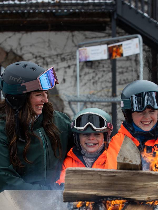 A family in ski gear by a bonfire