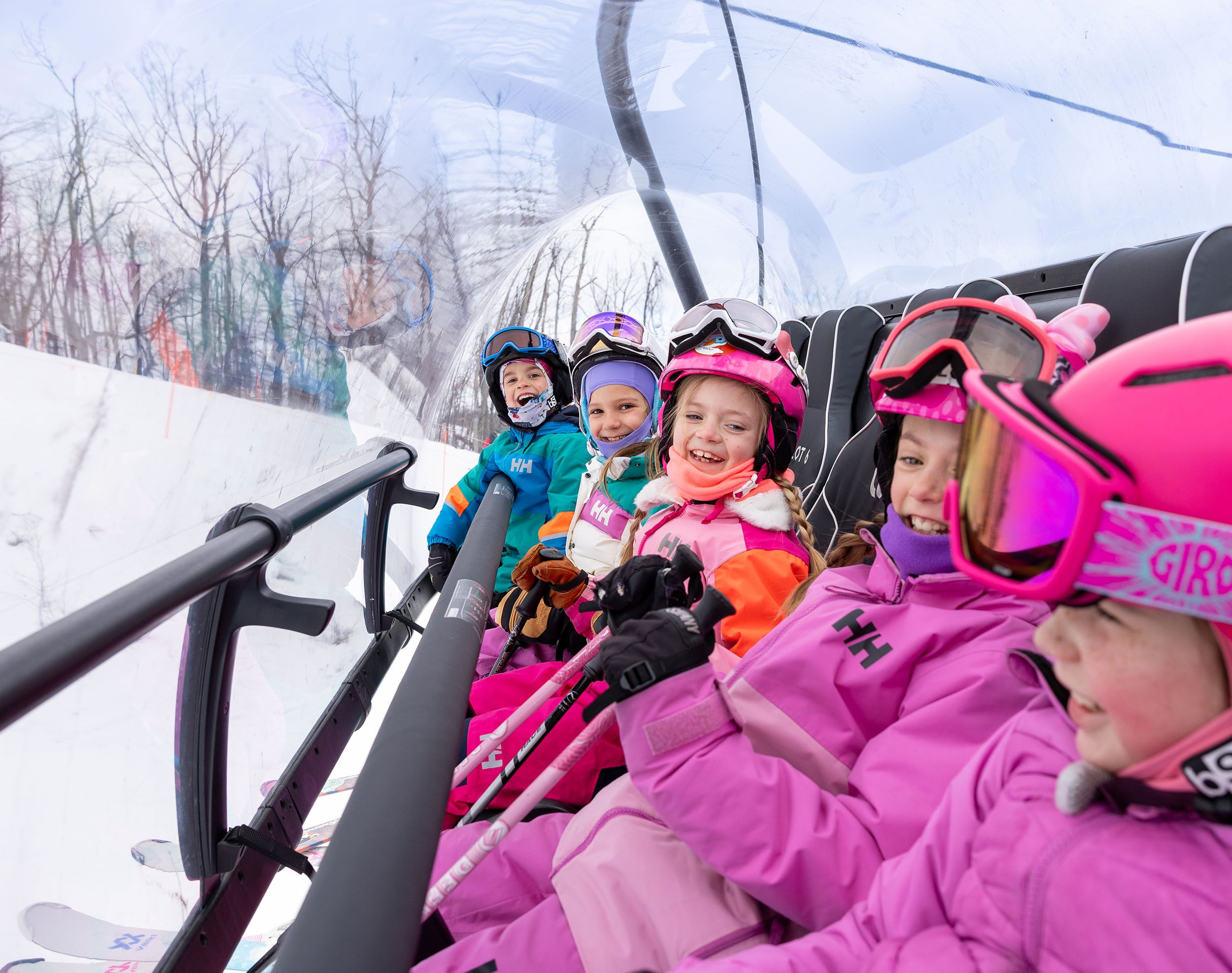 A group of kids in ski gear on the Camelot 6 chairlift at The Highlands