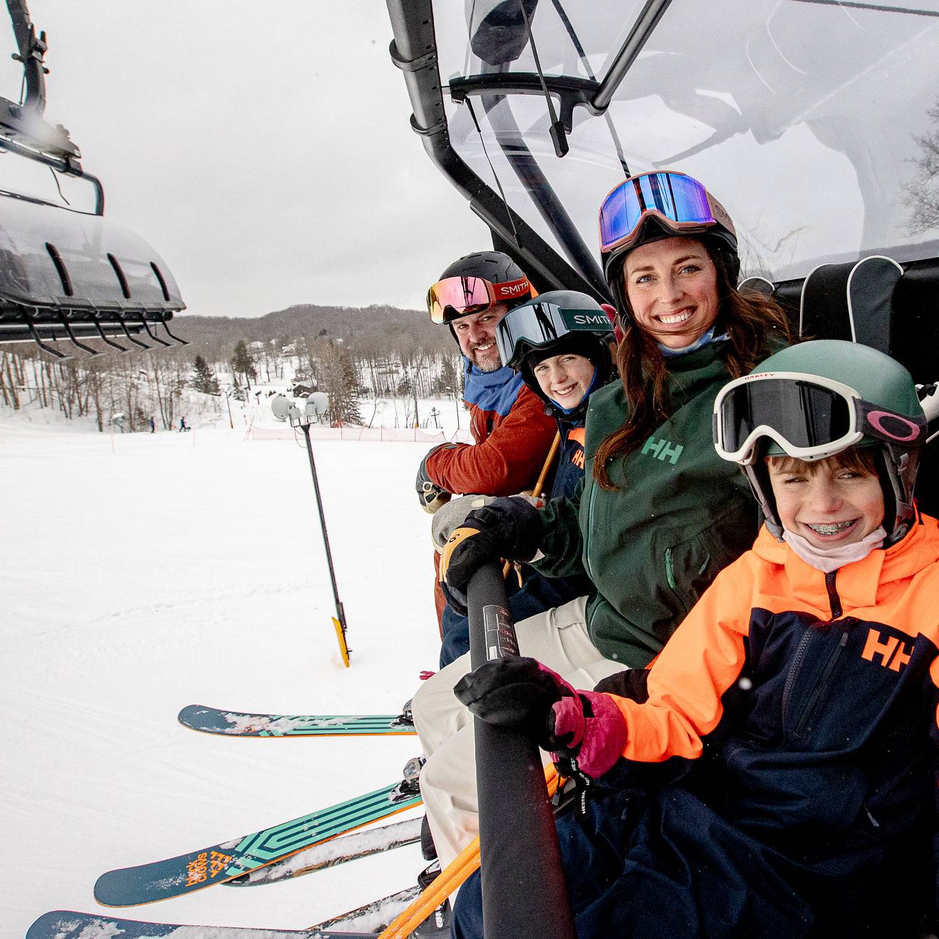 A family posing in ski gear on Camelot 6 chairlift at The Highlands