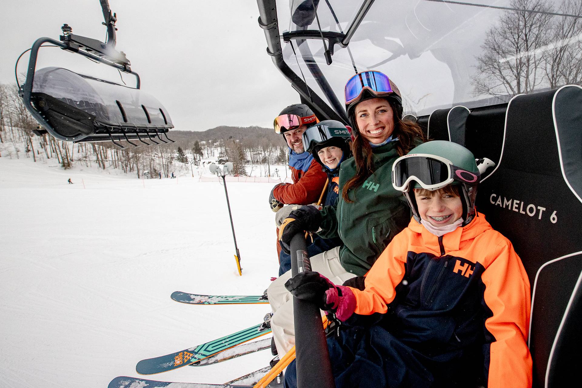 A family in ski gear on the Camelot 6 chairlift at The Highlands