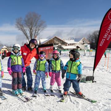 A group of ski instructors and kids smiling and posing for Ski Camp