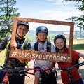 A group of kids holding a wooden frame sign smiling on mountain bikes