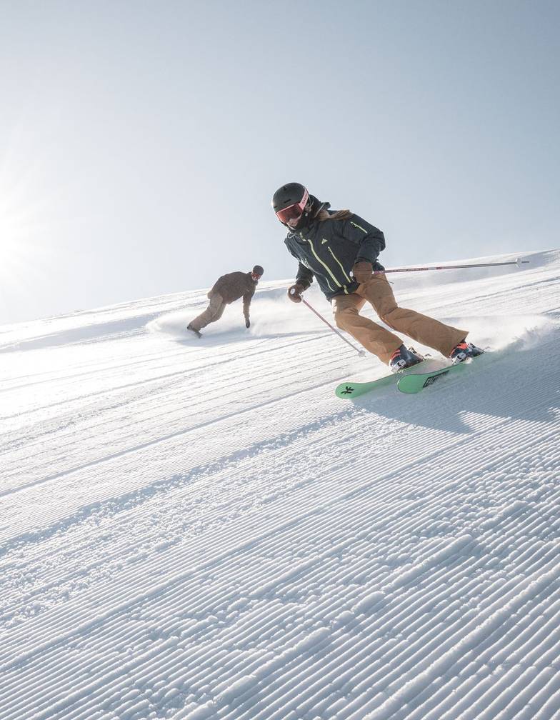 A skier and snowboarded on fresh corduroy.
