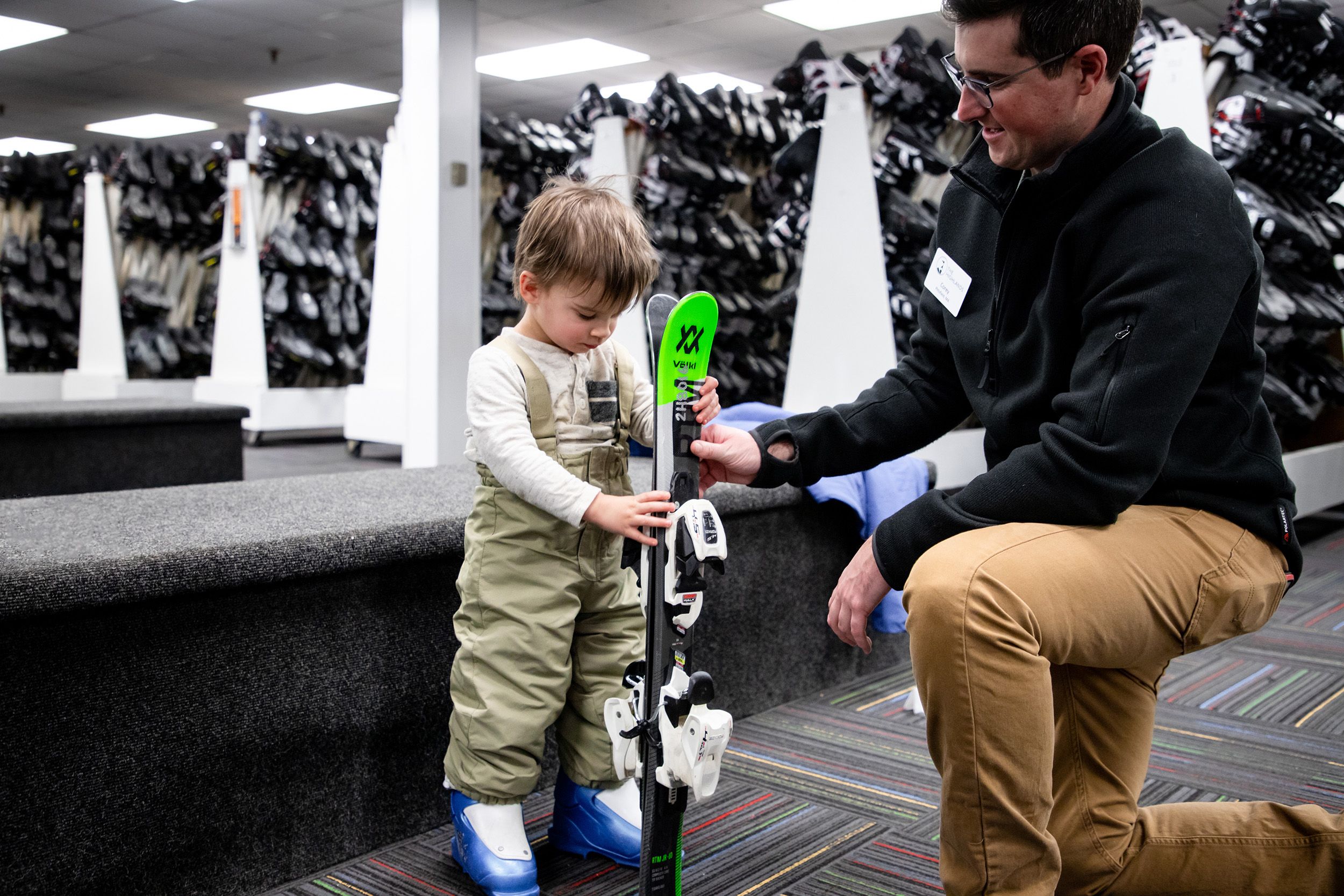 A child holding skis getting fitted for rental equipment at The Highlands