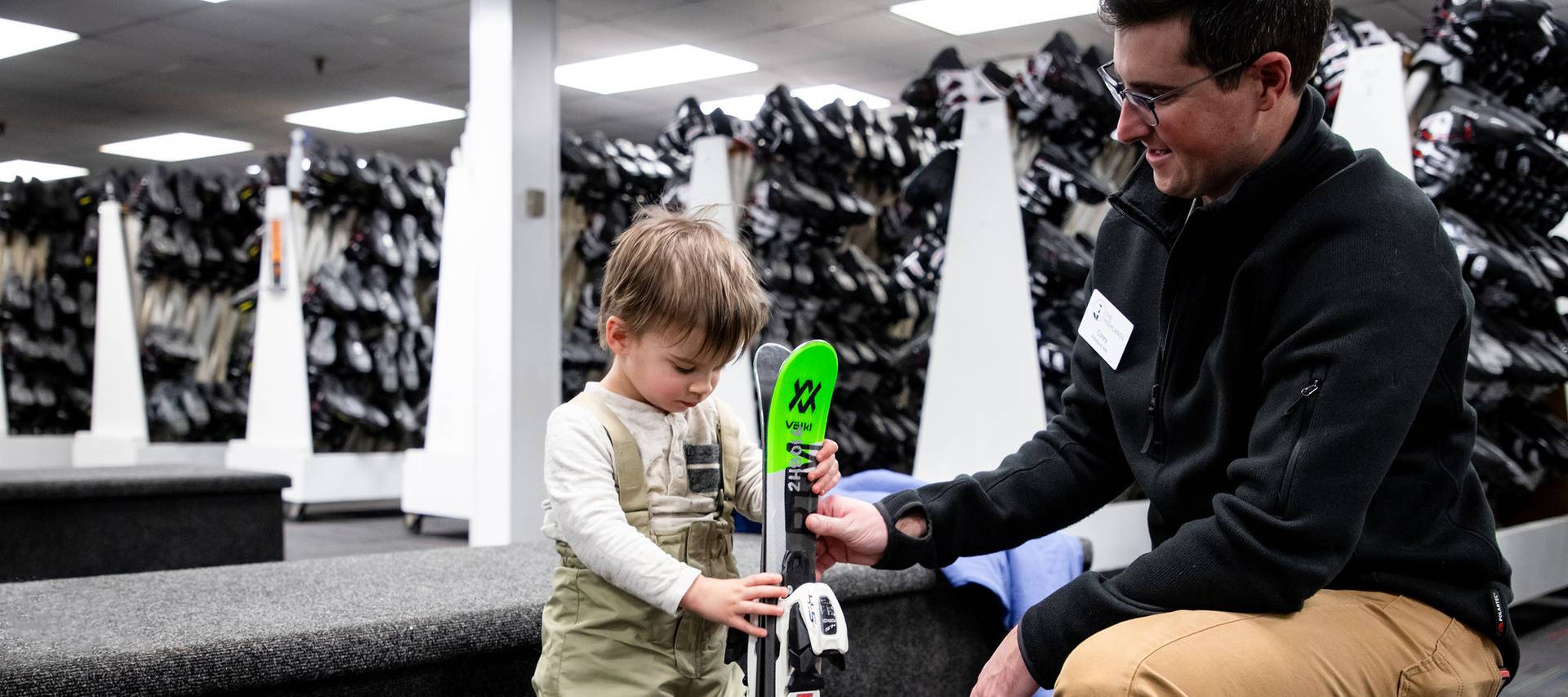 A child holding skis getting fitted for rental equipment at The Highlands