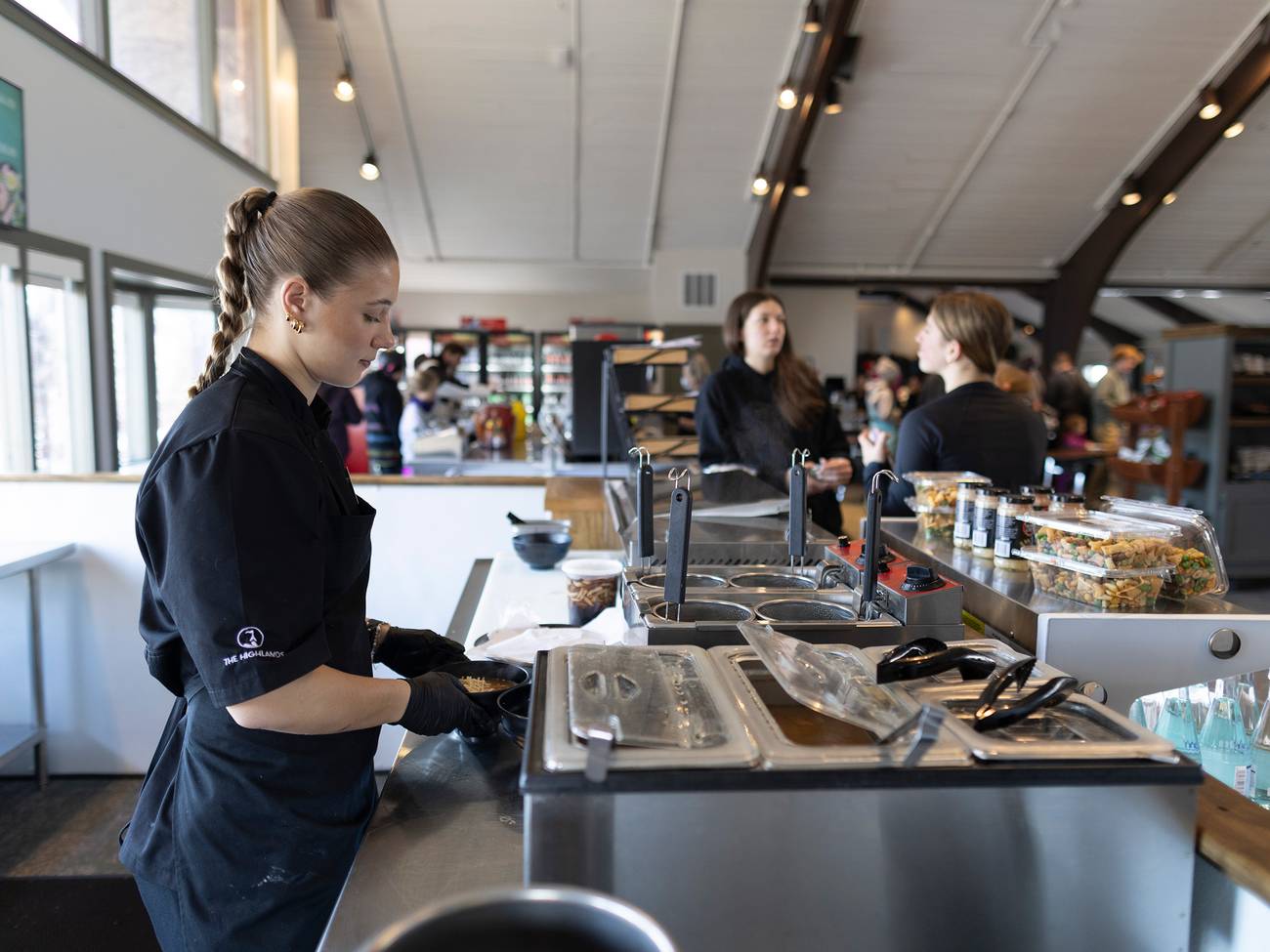 A woman putting together ramen in the Food Market at The Highlands