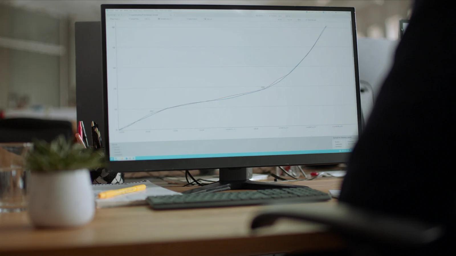 Mann am Monitor mit einer Sichtbarkeitskurve, die über zwölf Monatsmarken ansteigt