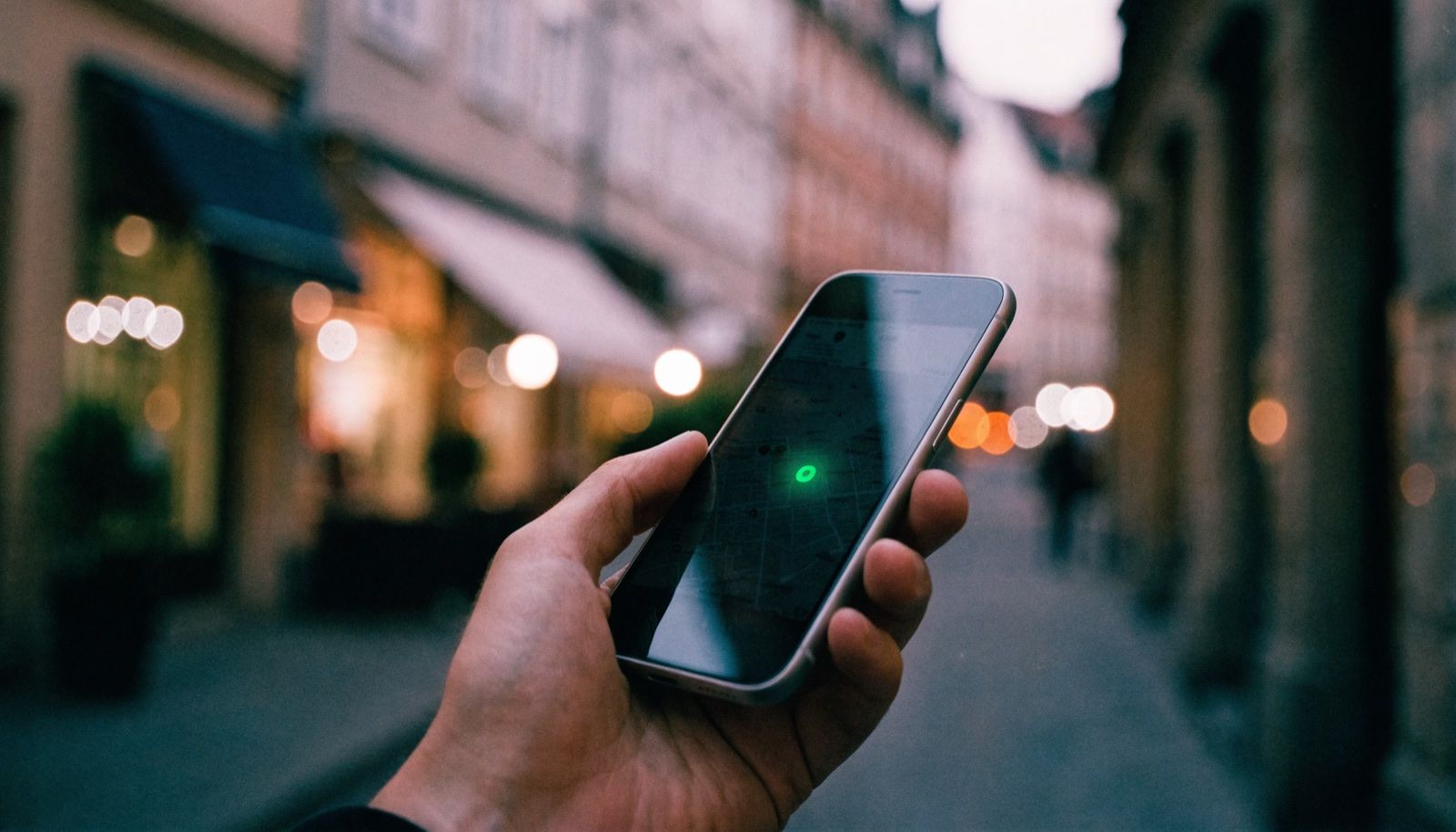Hand hält ein Smartphone mit Kartenansicht in einer Altstadtgasse