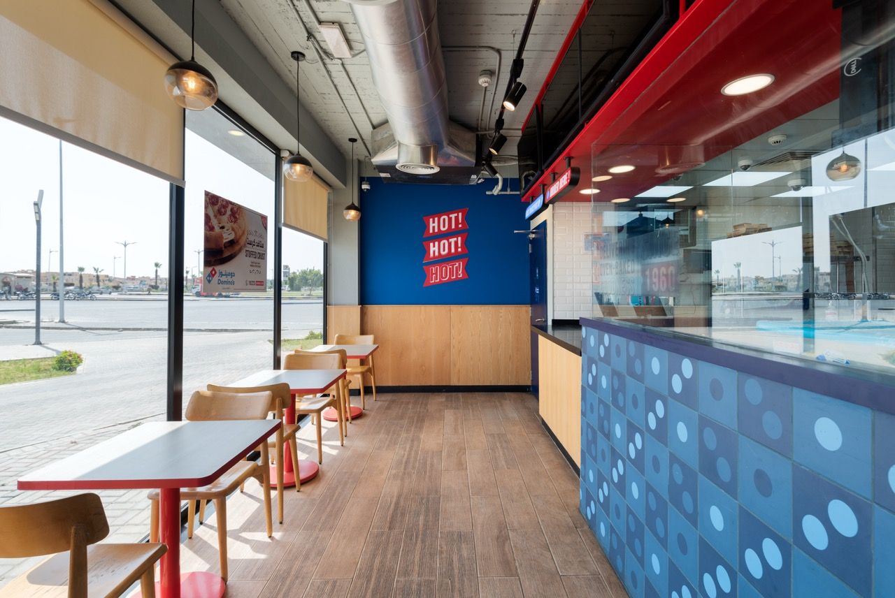 A wide-angle, exterior view of the **Lloyd's Building** in London, showcasing its distinctive inside-out architecture with exposed pipes, ducts, and service elements on the facade. The building stands tall against the skyline, reflecting the surrounding urban environment.