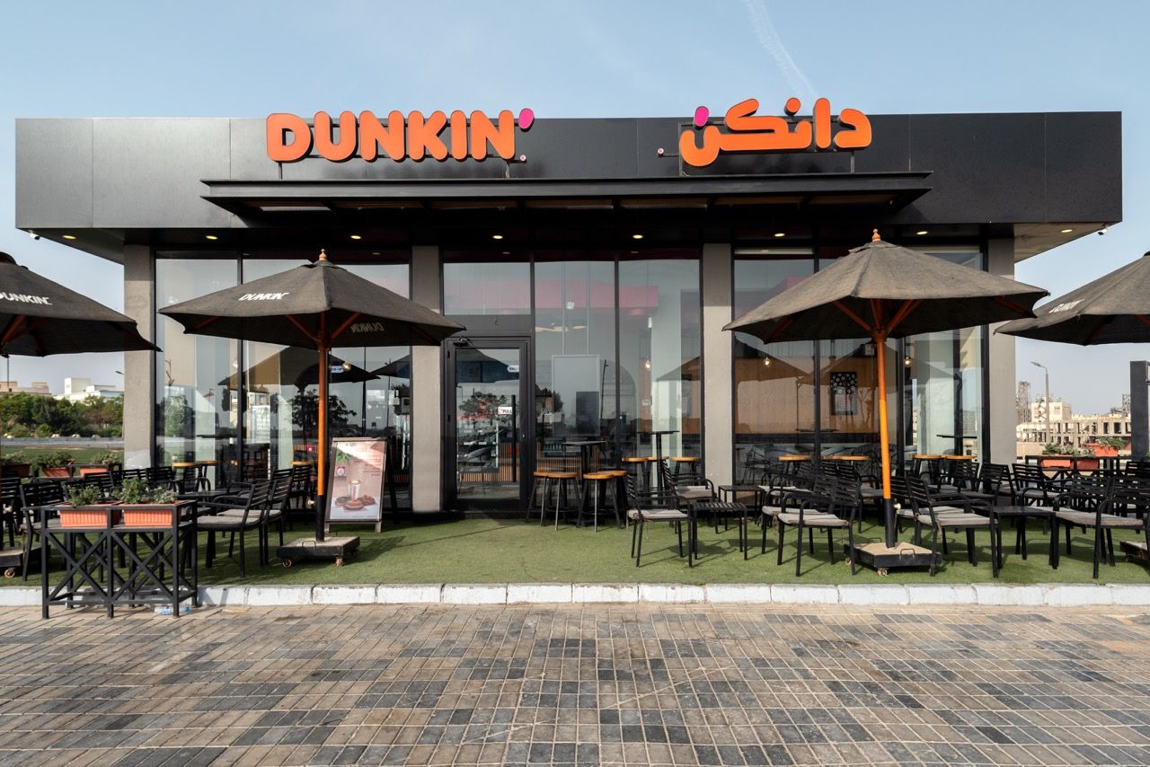 A wide-angle, exterior view of the **Lloyd's Building** in London, showcasing its distinctive inside-out architecture with exposed pipes, ducts, and service elements on the facade. The building stands tall against the skyline, reflecting the surrounding urban environment.