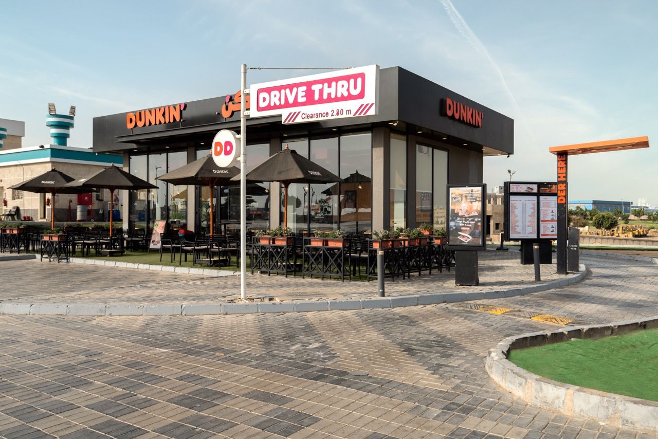 A wide-angle, exterior view of the **Lloyd's Building** in London, showcasing its distinctive inside-out architecture with exposed pipes, ducts, and service elements on the facade. The building stands tall against the skyline, reflecting the surrounding urban environment.