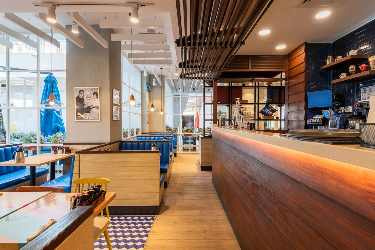 A wide-angle, exterior view of the **Lloyd's Building** in London, showcasing its distinctive inside-out architecture with exposed pipes, ducts, and service elements on the facade. The building stands tall against the skyline, reflecting the surrounding urban environment.