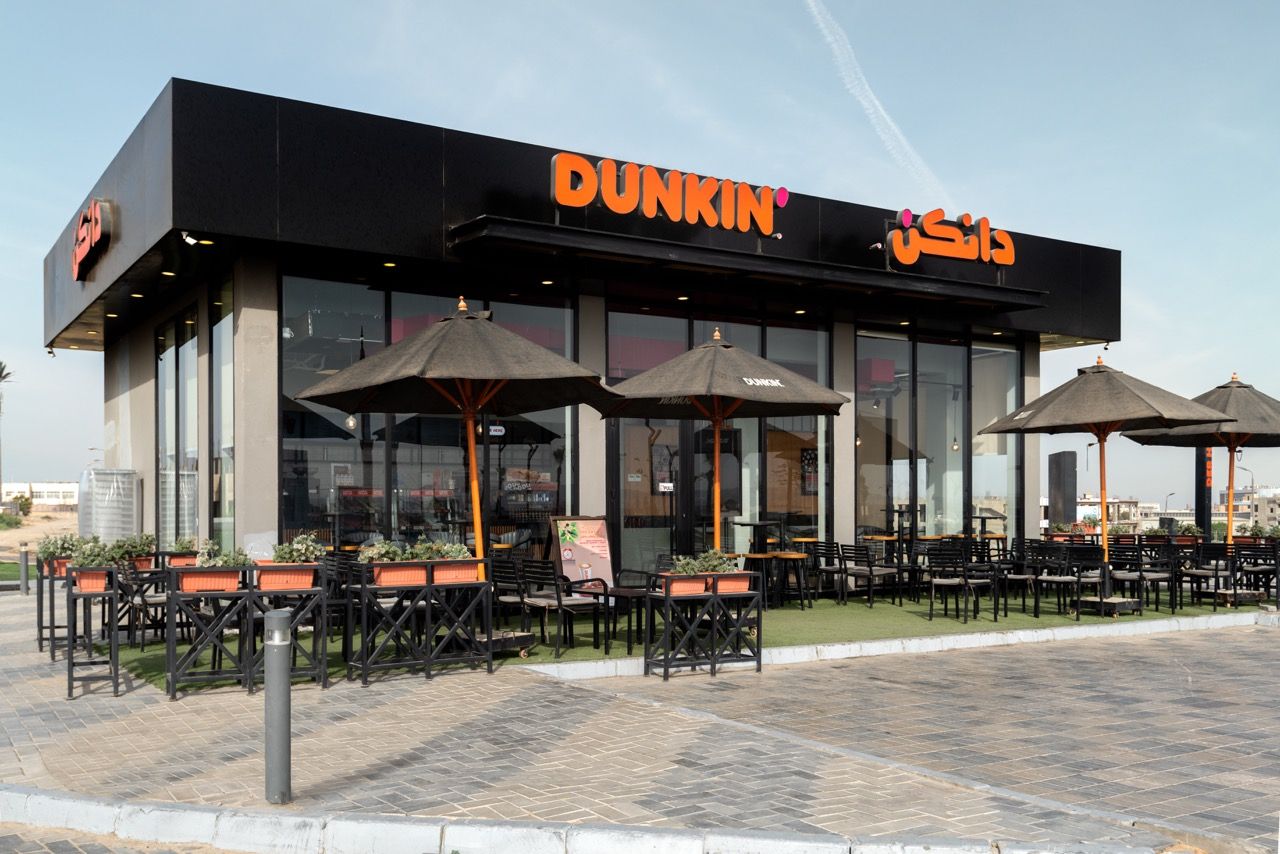 A wide-angle, exterior view of the **Lloyd's Building** in London, showcasing its distinctive inside-out architecture with exposed pipes, ducts, and service elements on the facade. The building stands tall against the skyline, reflecting the surrounding urban environment.