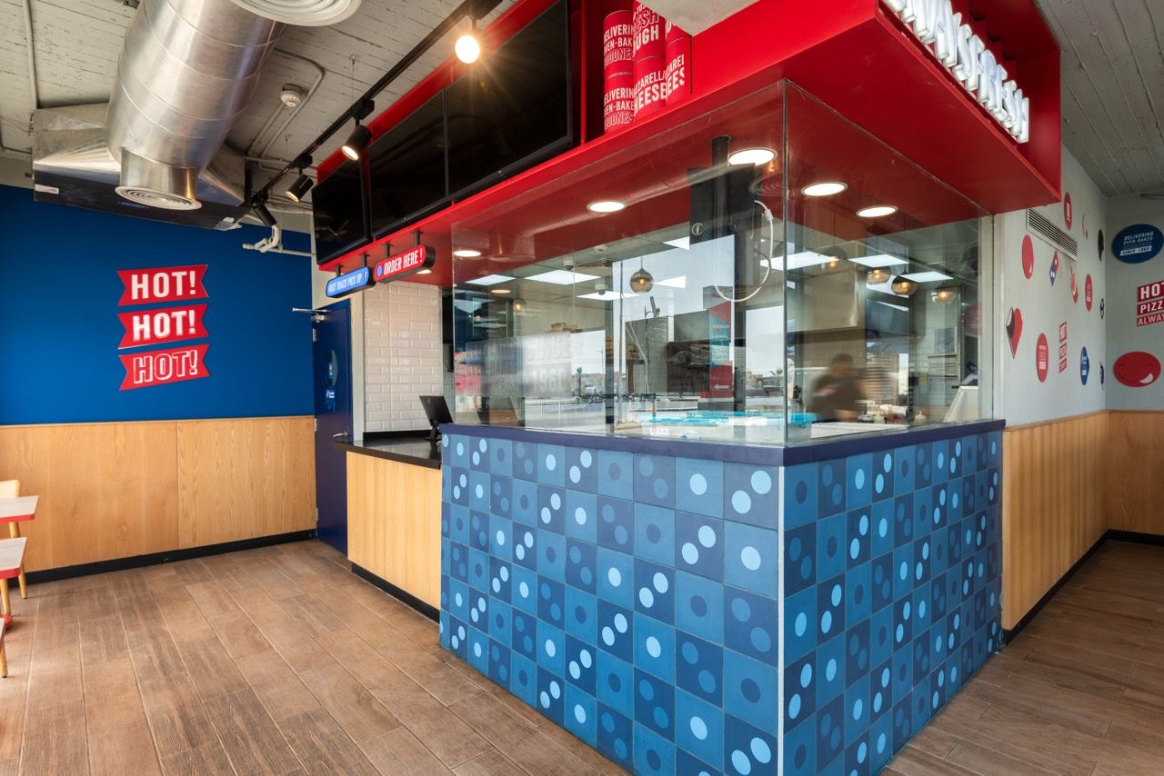 A wide-angle, exterior view of the **Lloyd's Building** in London, showcasing its distinctive inside-out architecture with exposed pipes, ducts, and service elements on the facade. The building stands tall against the skyline, reflecting the surrounding urban environment.