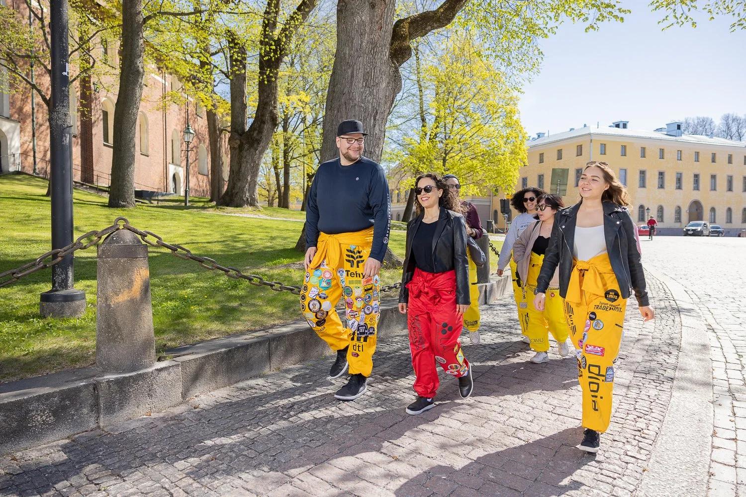 Opiskelijoita haalareissa kävelemässä kevätpuistossa.
