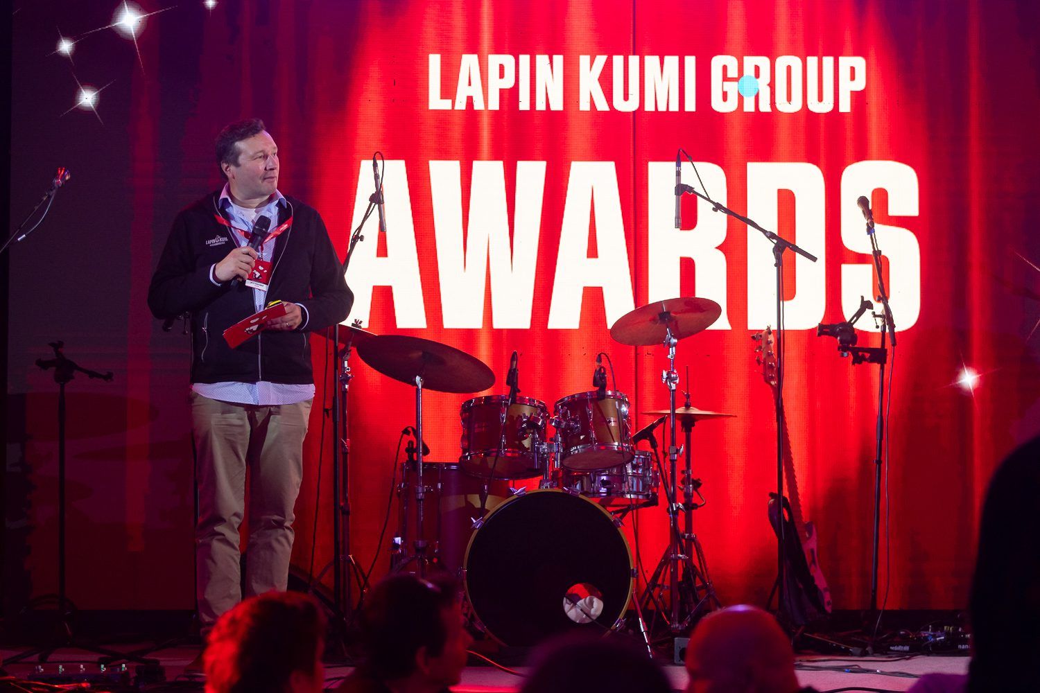 Lavan ruudulla lukee Lapin Kumi Group Awards, puhujalla punaiset kortit kädessään.