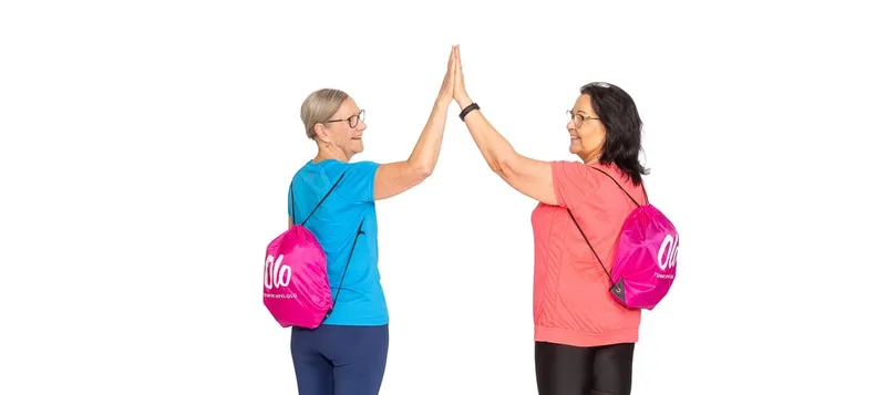 Kaksi treeniasuista naista lyö yläfemmat, selässä pinkit Olo-reput.