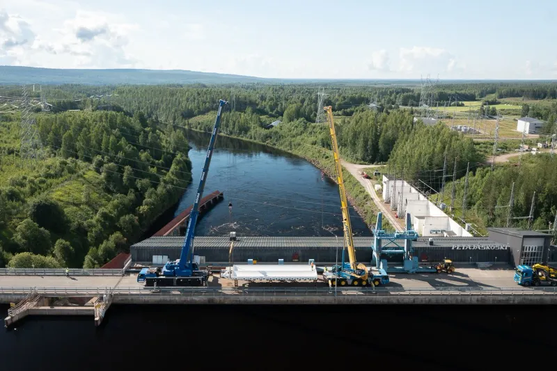 Sillan rakennustyömaa joen yli metsäisessä maisemassa.