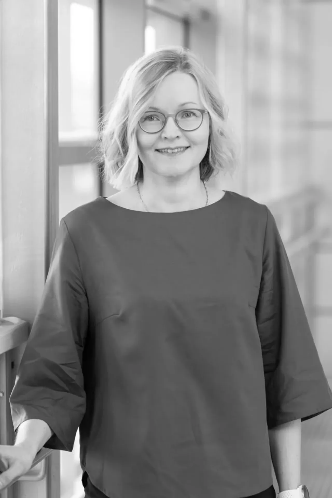 Mustavalkoinen muotokuva silmälasipäisestä naisesta.