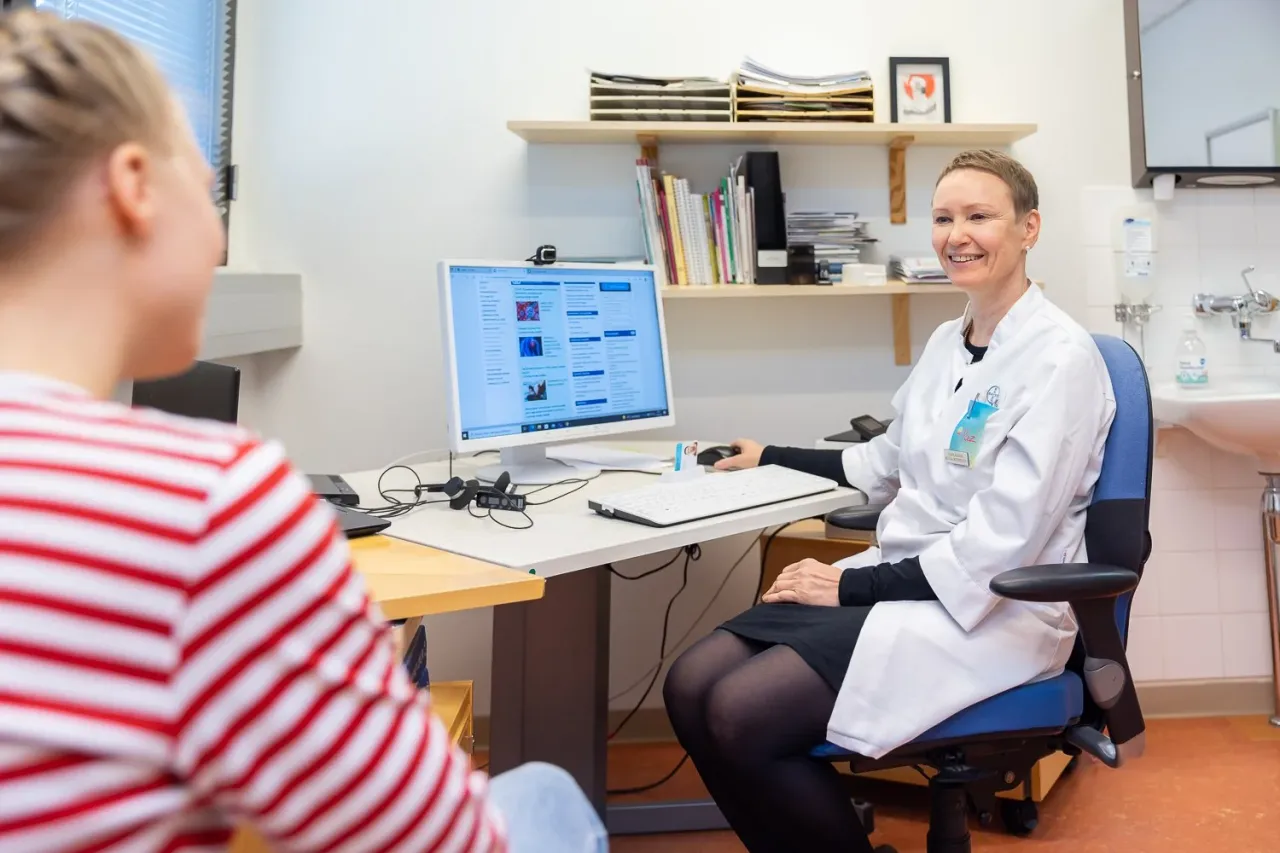 Lääkäri työpisteellään näytön ääressä.