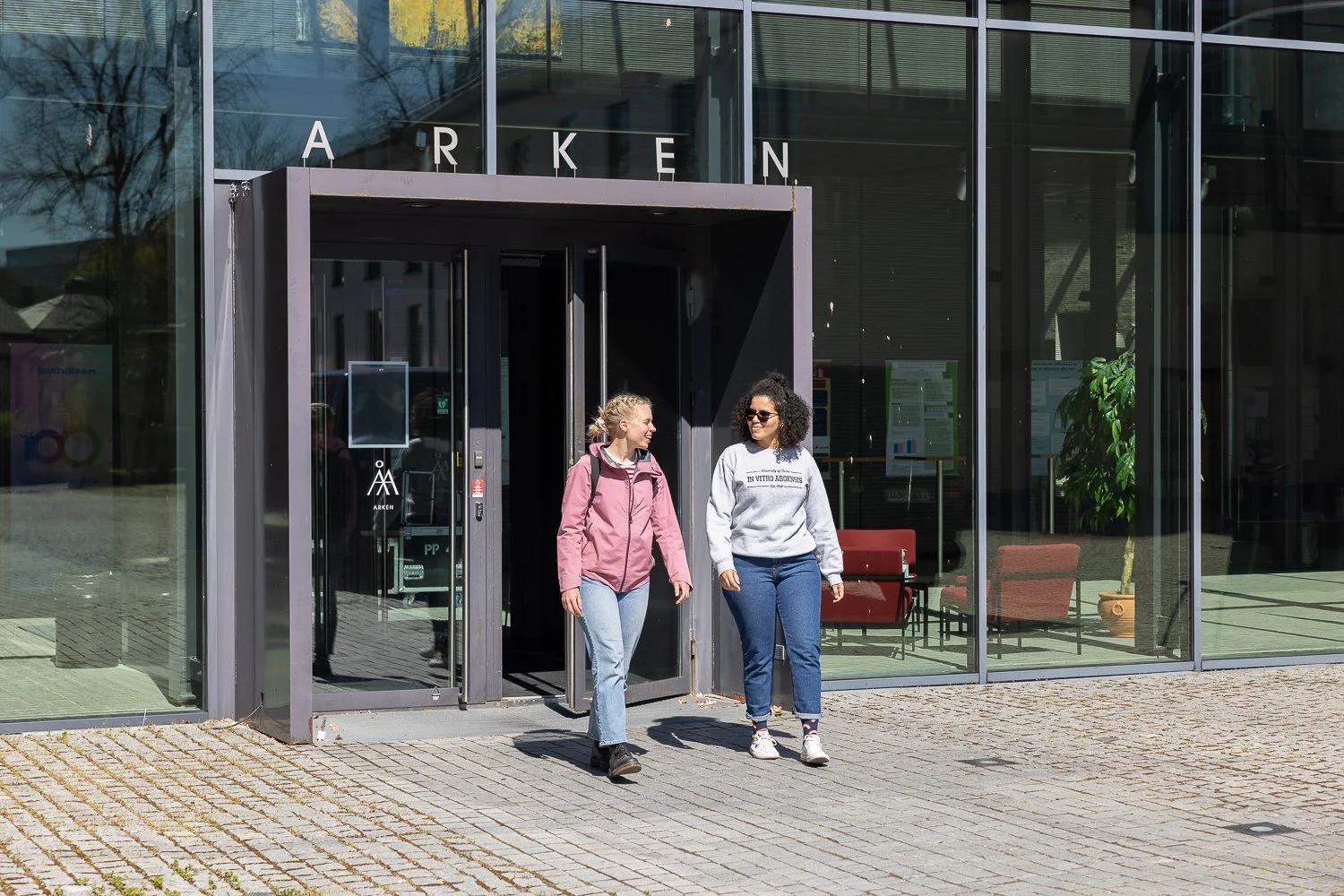 Opiskelijoita kampusrakennuksen lasiovilla.