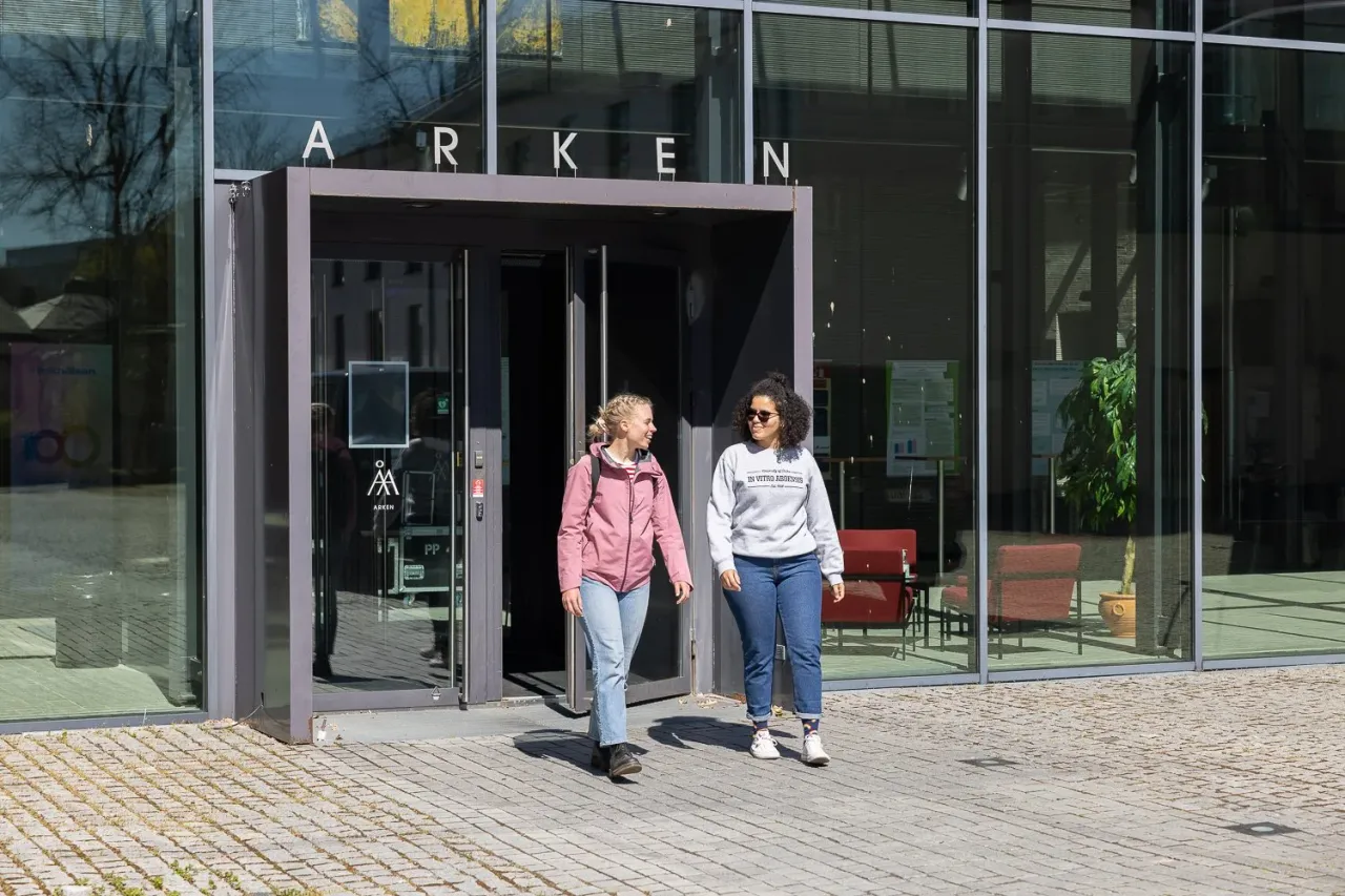 Opiskelijoita kampusrakennuksen lasiovilla.
