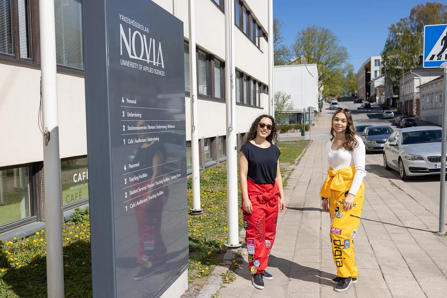 Opiskelijoita korkeakoulun opastekyltin edessä.