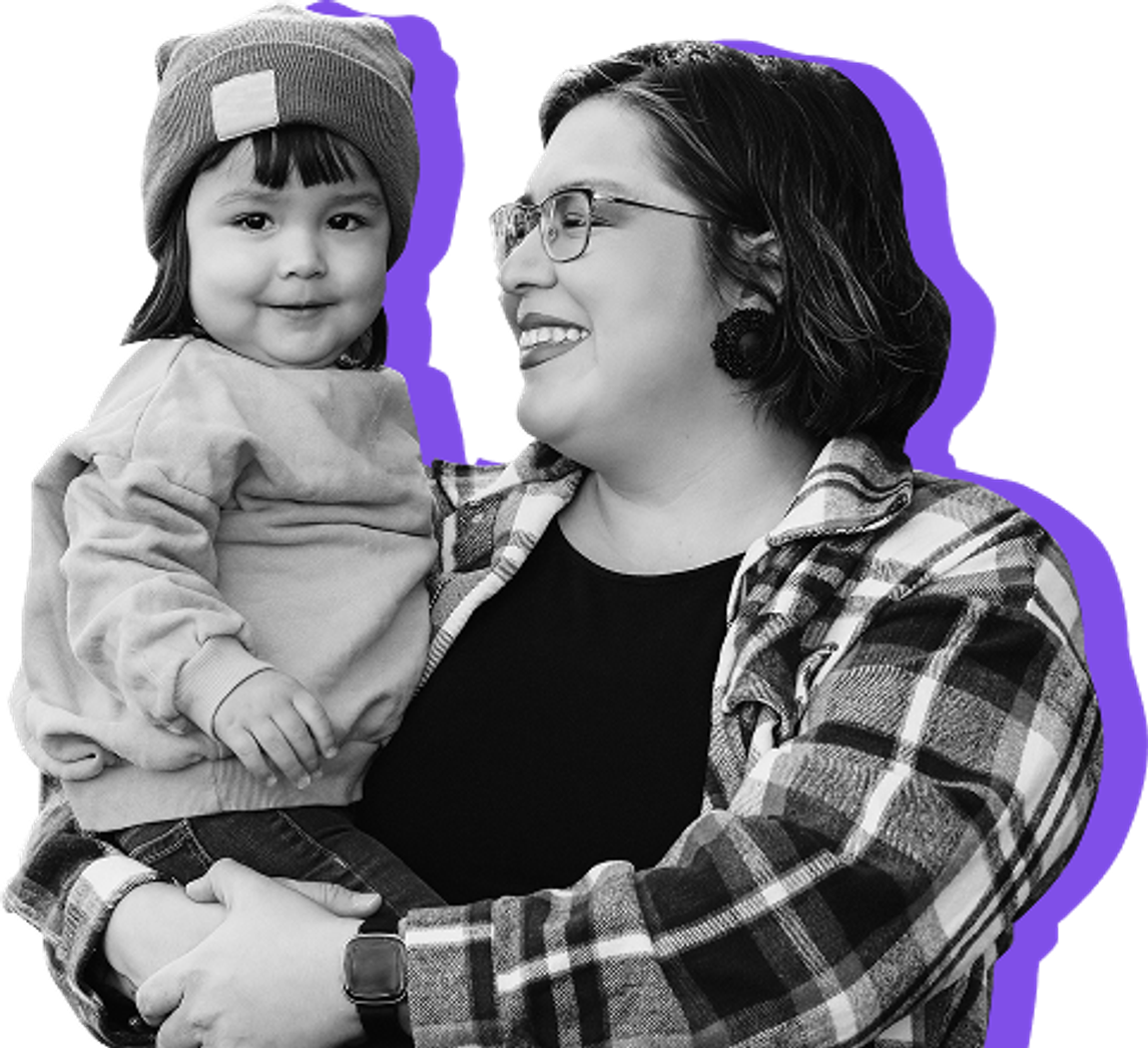 A mom holds her toddler daughter against a purple background.