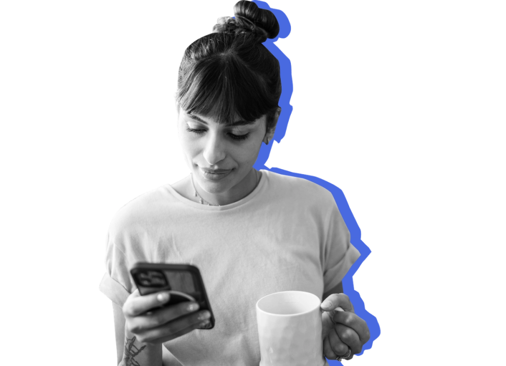 Woman holding coffee and looking at her phone. 