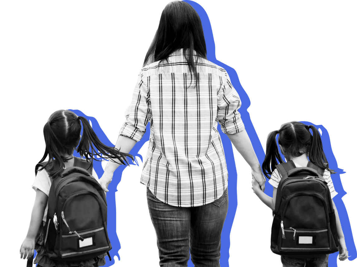 A mother holds the hands of her children as she walks them to school.