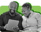 A woman and man smile while looking at an iPad screen. 