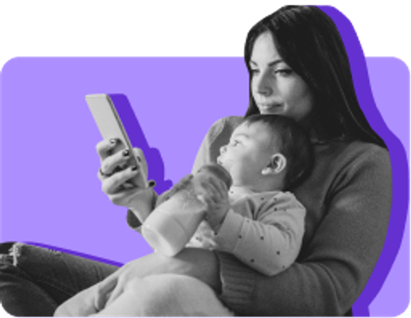 Mother holding infant in lap while looking at her phone