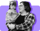 A mom holds her toddler daughter against a purple background.
