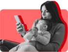 A woman holding her baby looks at her phone