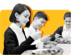Students sit together eating lunch against a yellow backdrop