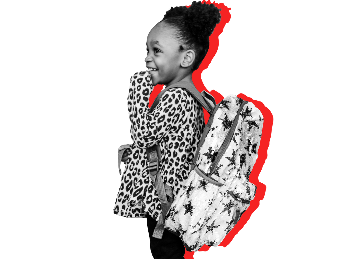 A child in a backpack smiles against a red background. Head Start programs are free for low-income families. 