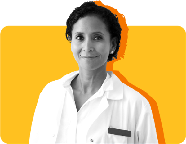 A dentist who accepts Medicaid looks at the camera, wearing a white coat against a yellow background