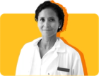 A dentist who accepts Medicaid looks at the camera, wearing a white coat against a yellow background