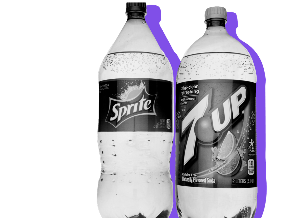 A bottle of Sprite and a bottle of 7 Up stand next to each other.