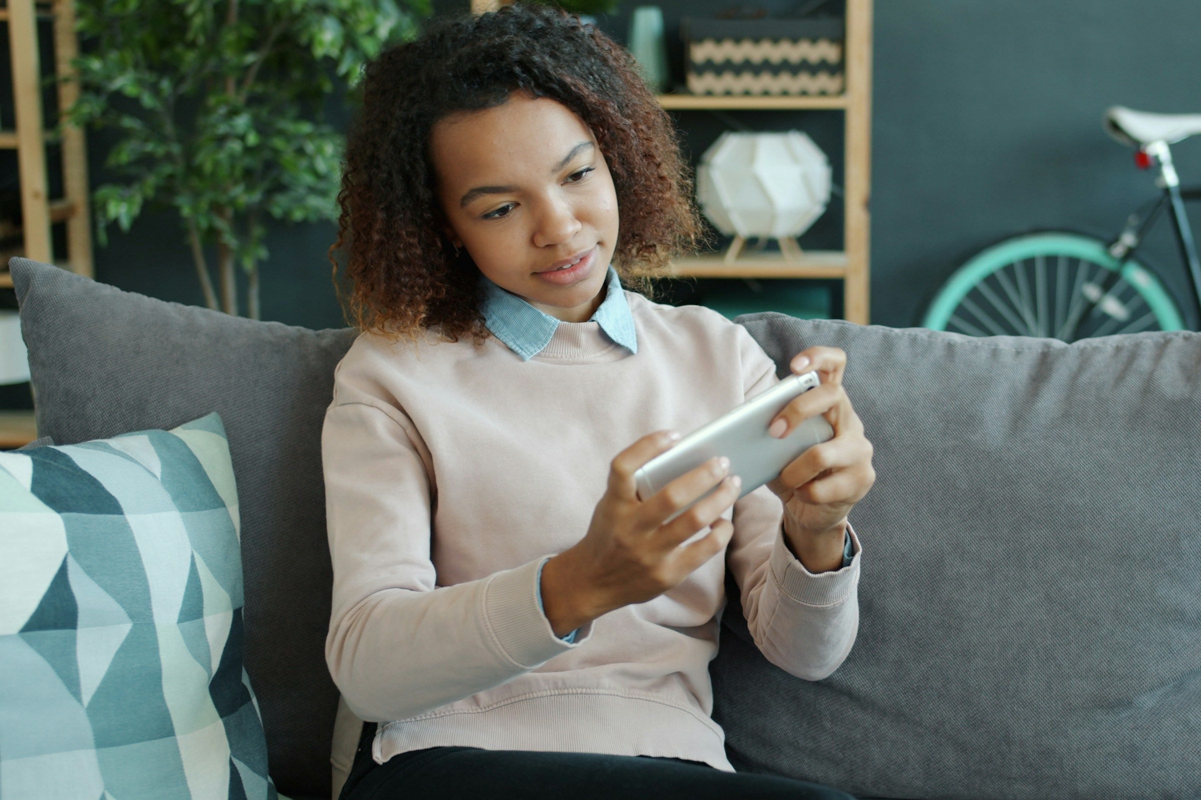 Young woman playing game on smartphone at home