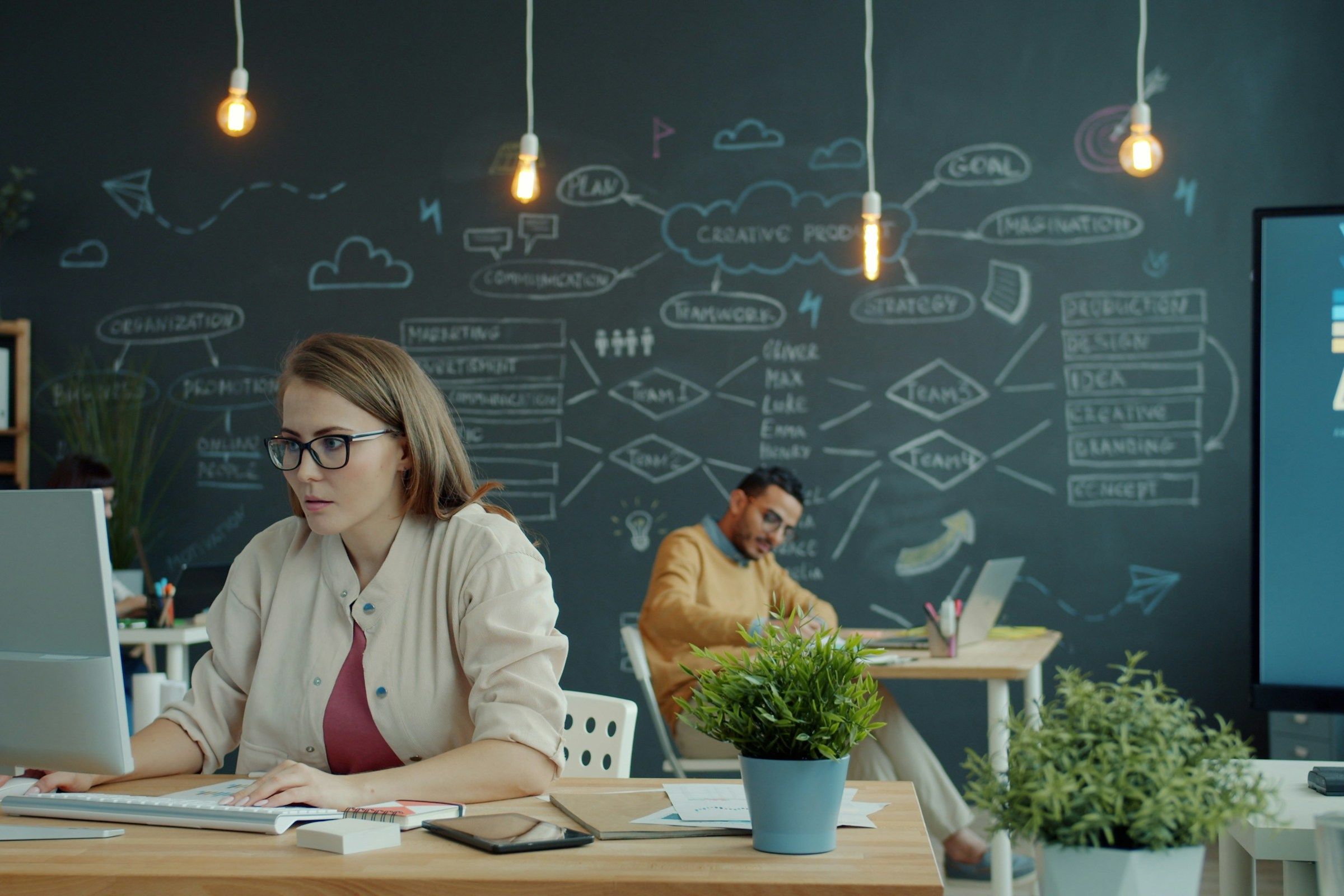 Woman working on computer in modern office with chalkboard